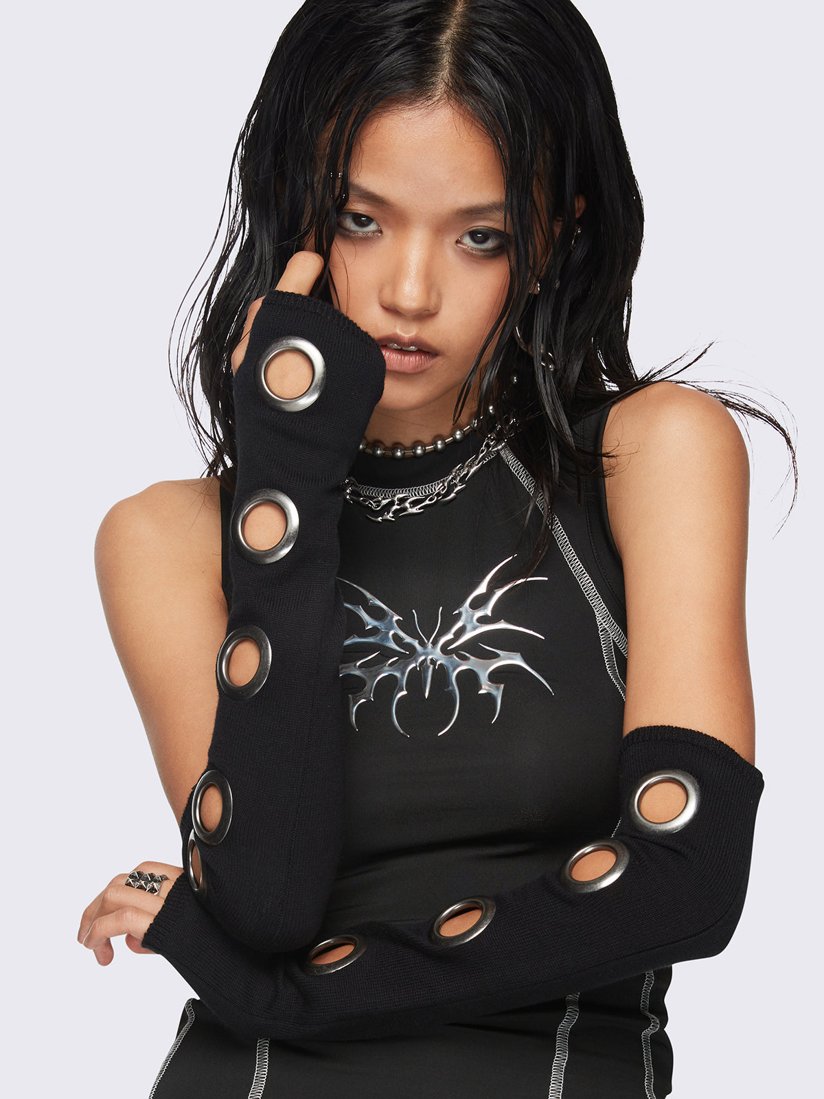 Black arm warmers with metallic hole details and thumbhole cuffs.