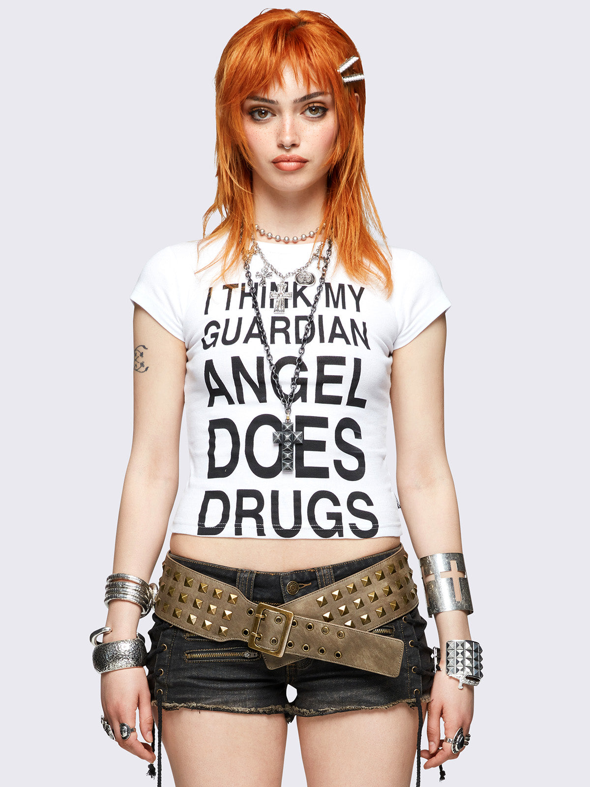 White baby tee with bold black "I think my guardian angel does drugs" front print, featuring a black cross back print.