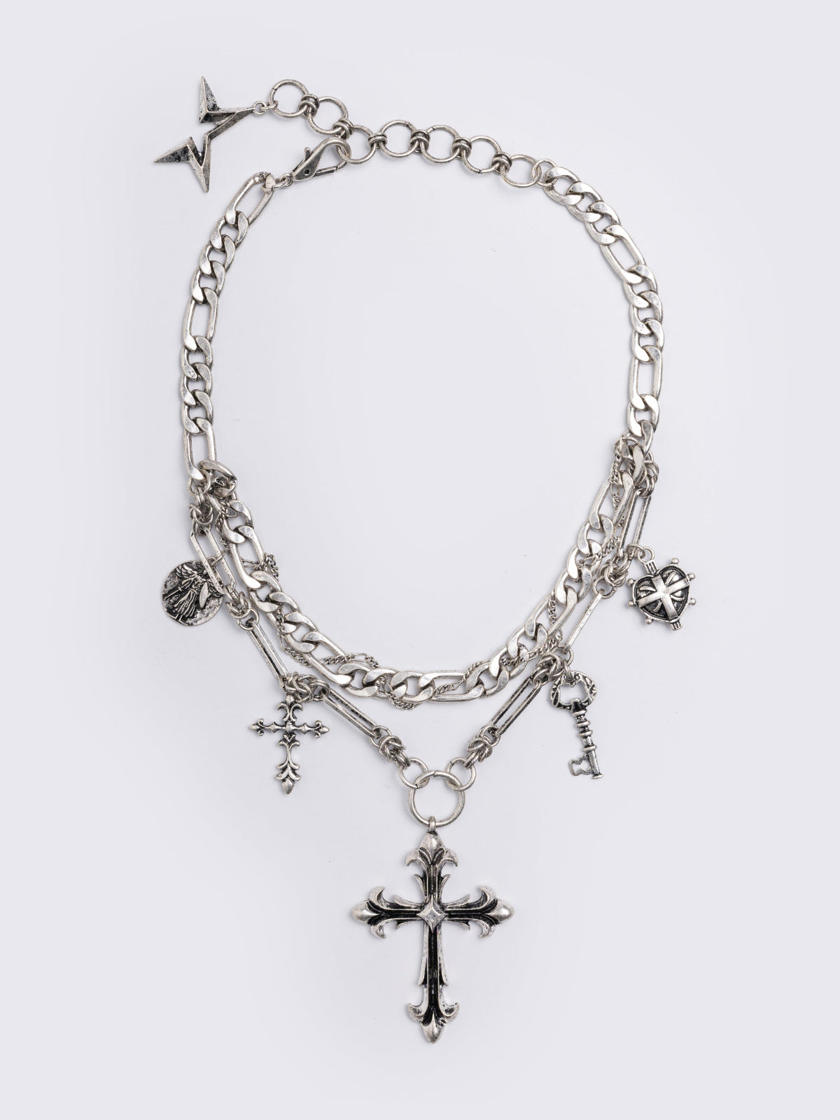 Silver chunky layered necklace featuring cross, key and medallion pendants.