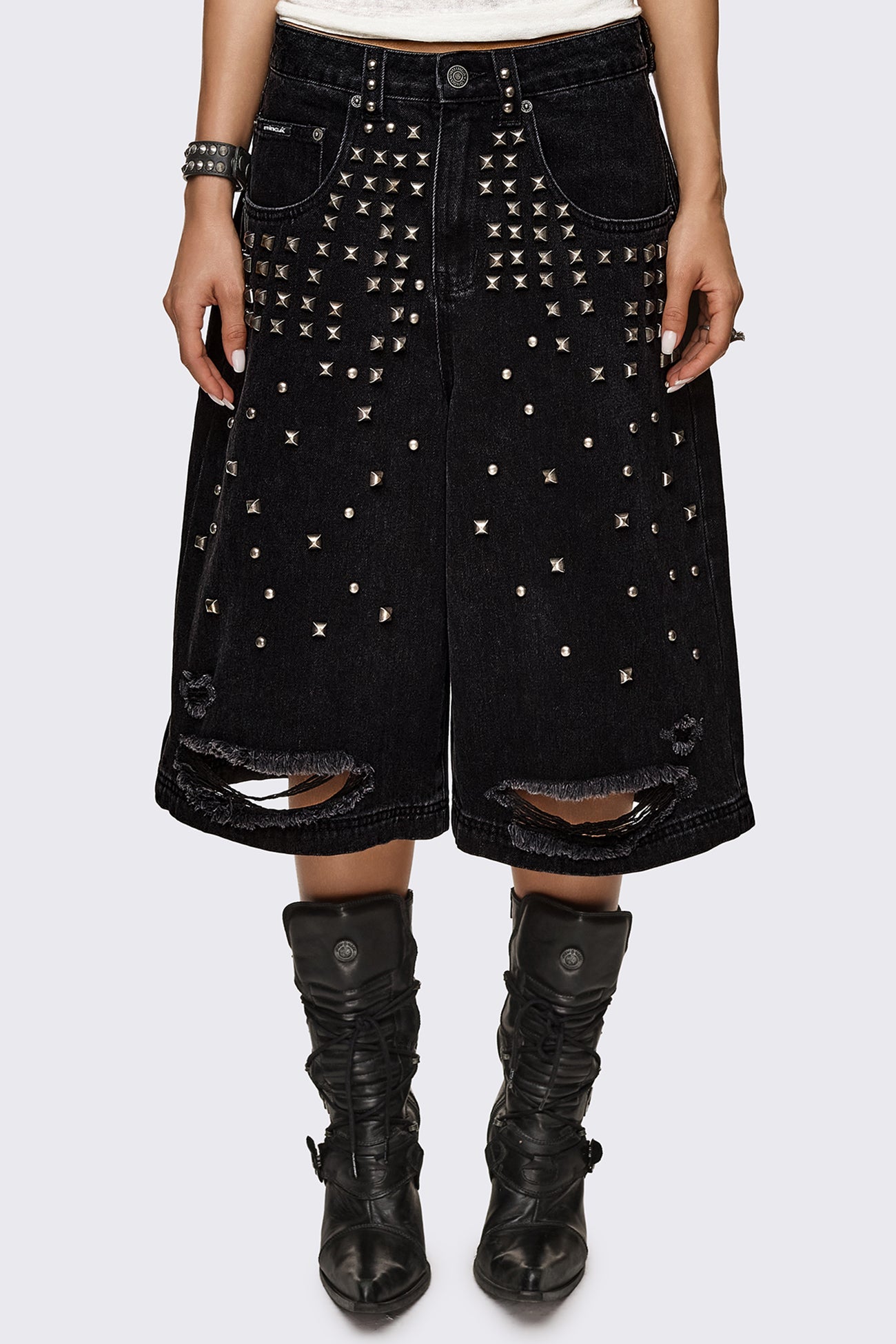 Black washed denim jorts with silver studs and ripped hems, baggy longline fit in a grunge aesthetic.