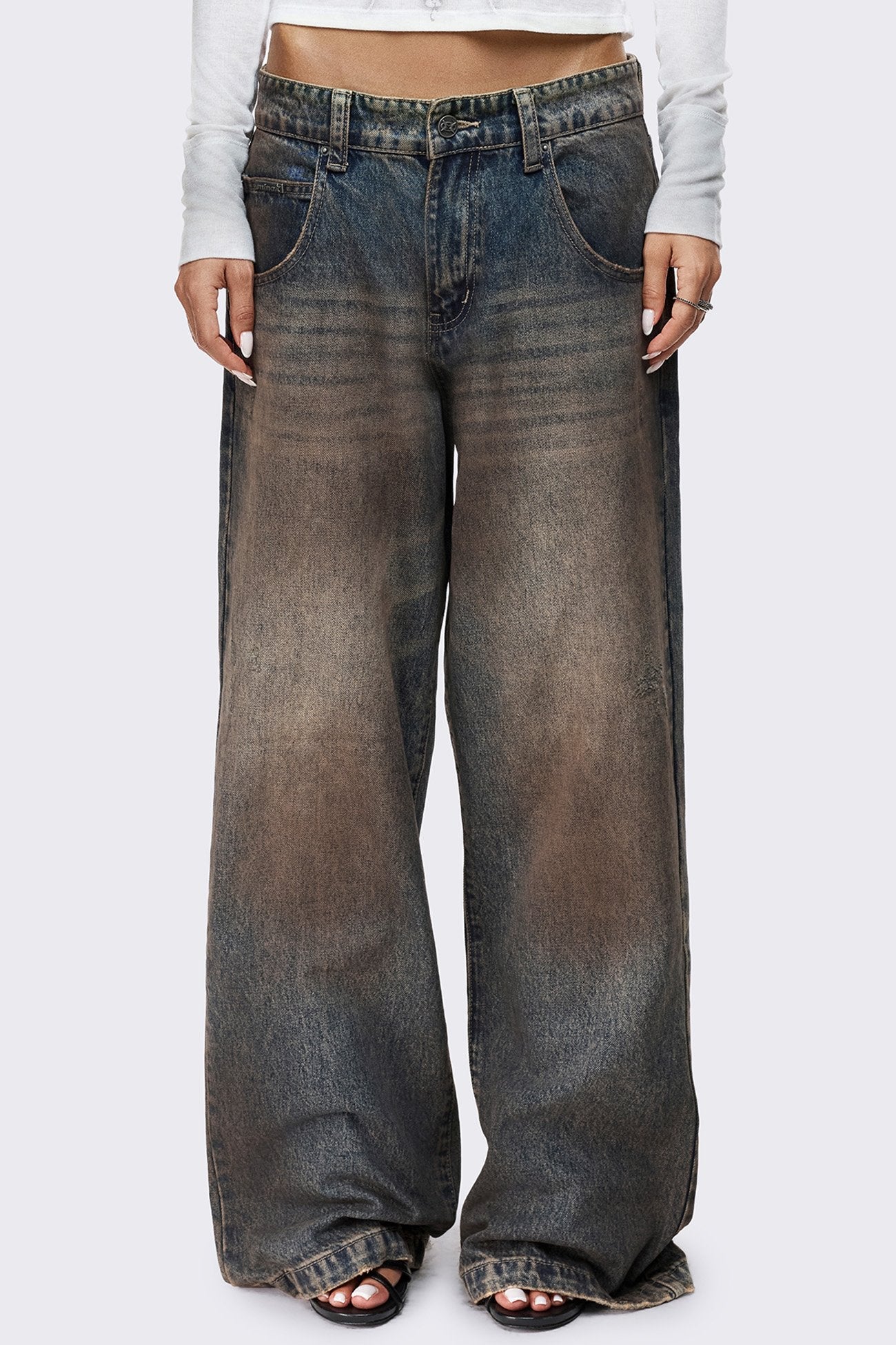 Blue dirty wash baggy jeans with brown mud overdye, low rise waist, wide legs and raw frayed hems.