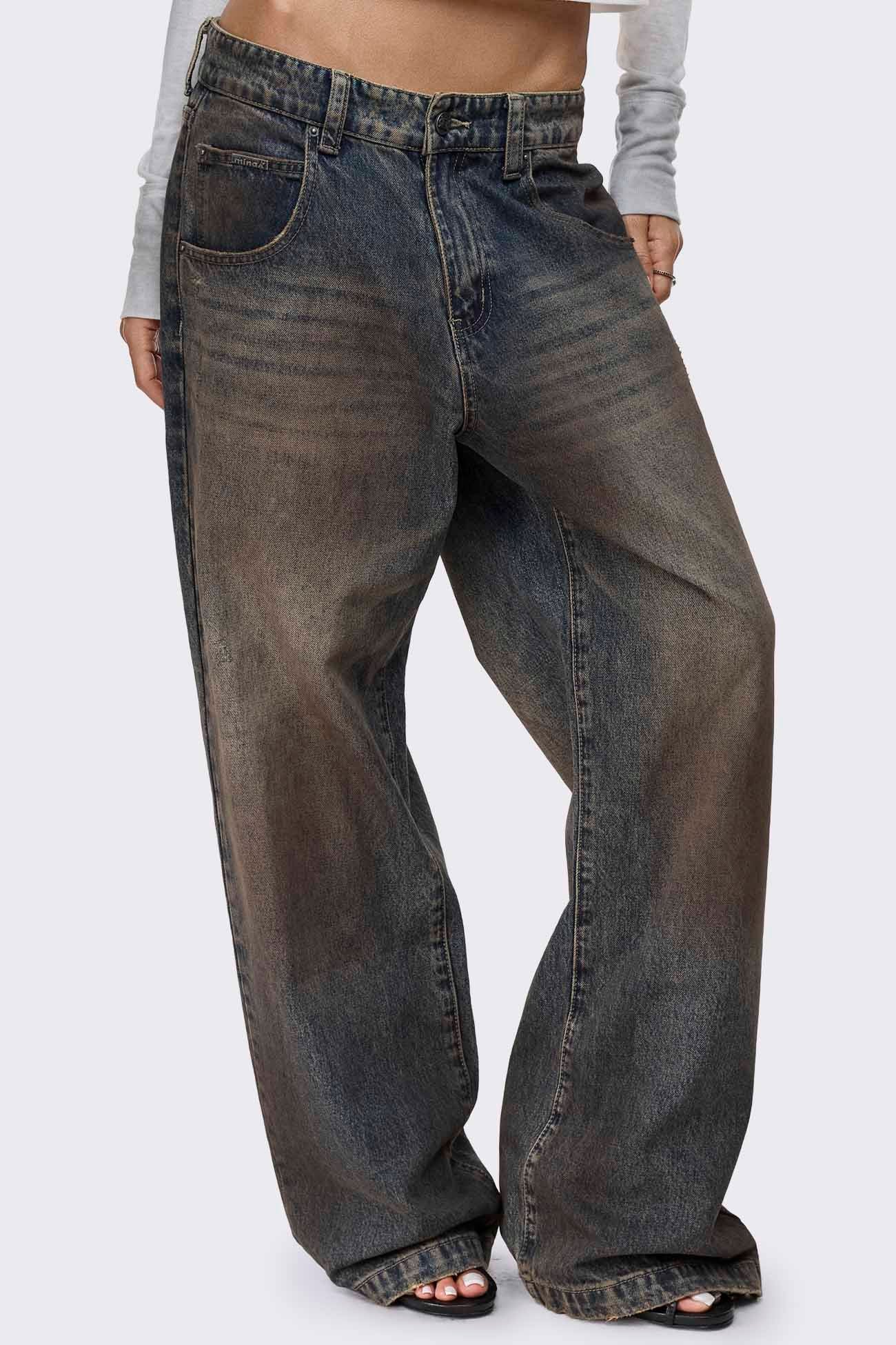 Blue dirty wash baggy jeans with brown mud overdye, low rise waist, wide legs and raw frayed hems.