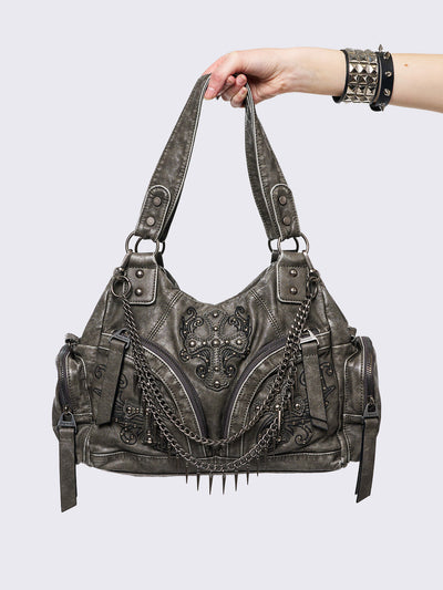 Grey washed faux leather shoulder bag with studded cross patches, spikes and chains accents. Multiple pockets and grunge-style.
