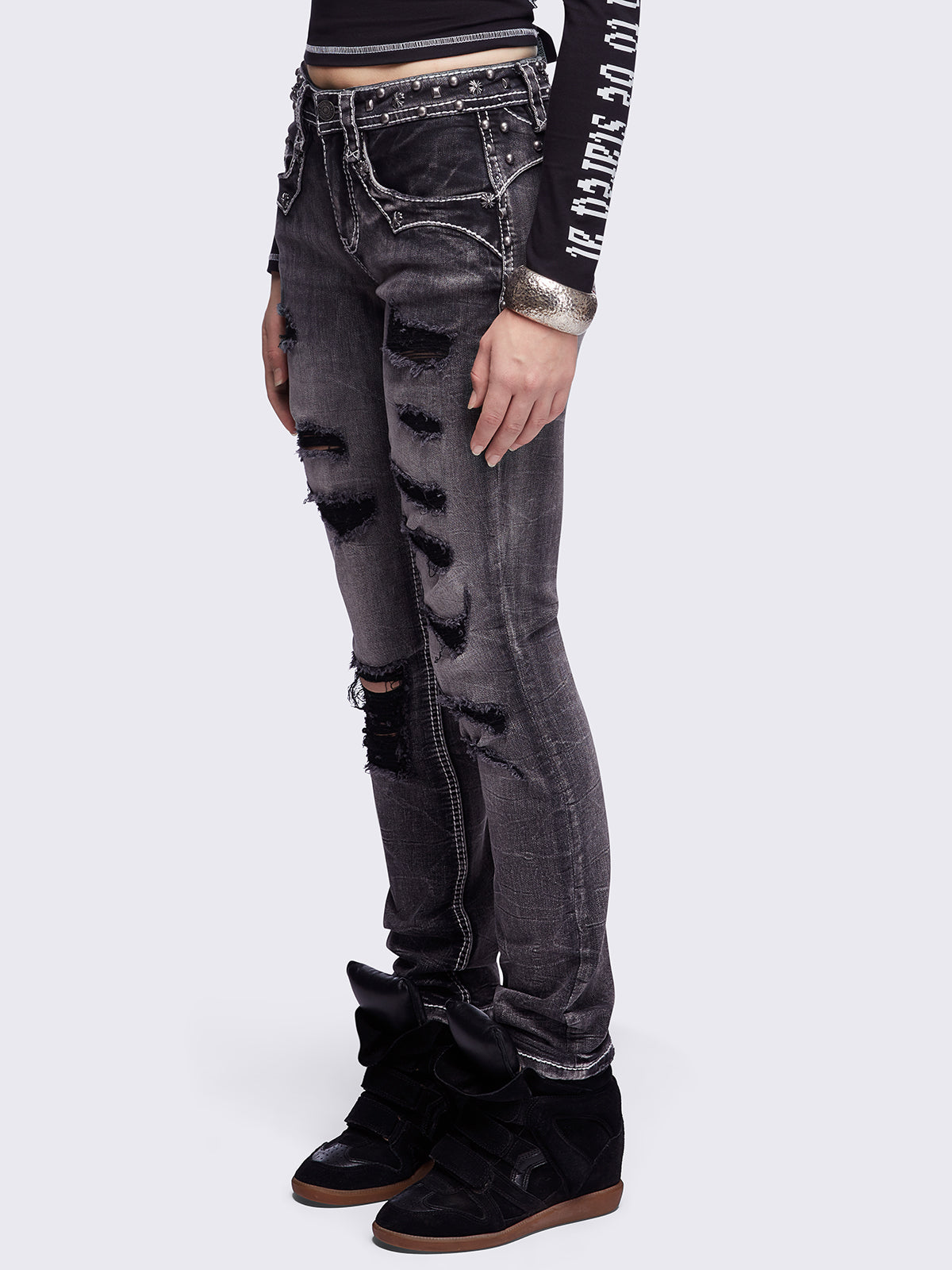 Black washed skinny jeans featuring ripped and stud details, white contrast stitching, embroidered back pocket and raw frayed hems.