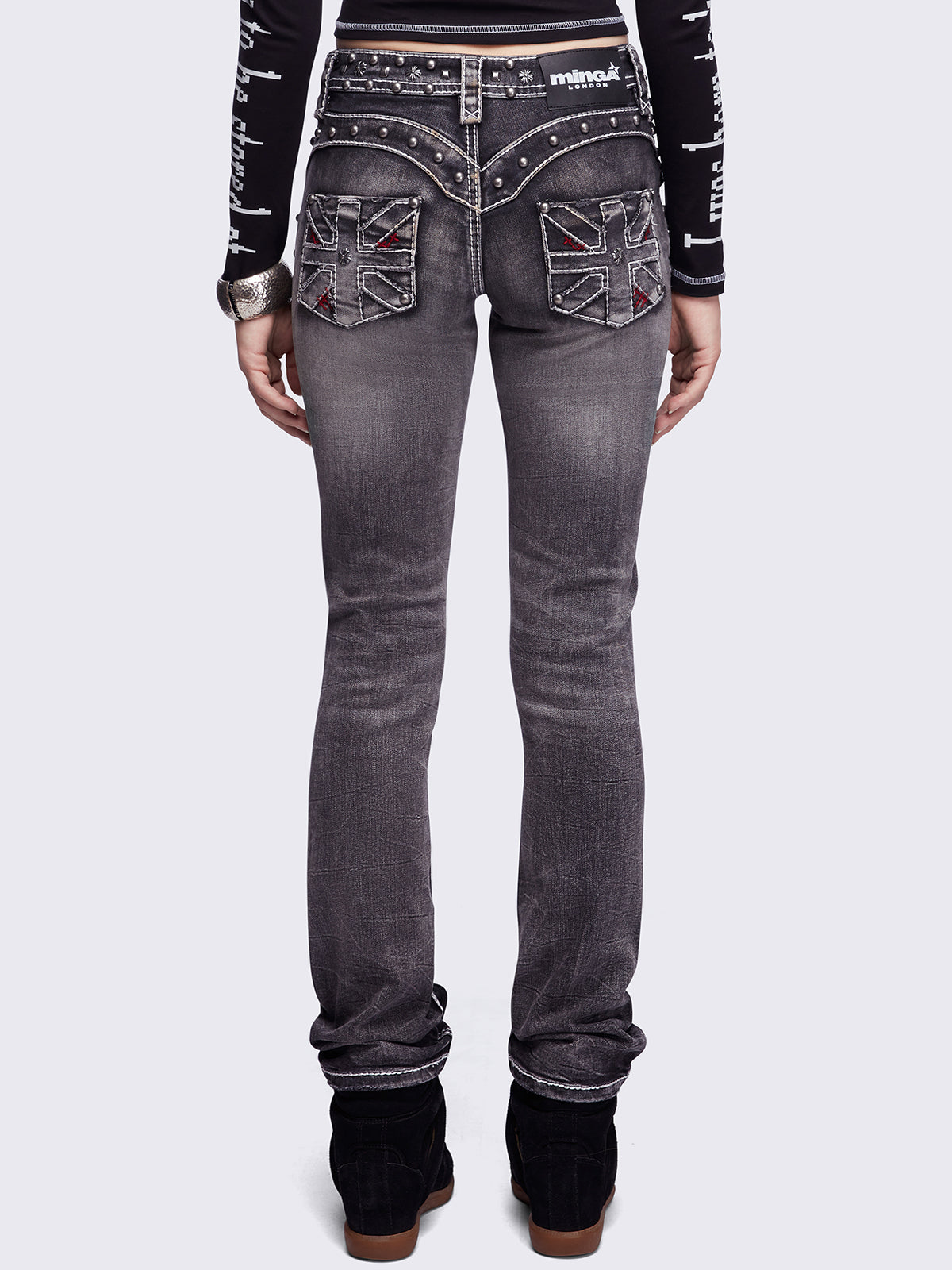 Black washed skinny jeans featuring ripped and stud details, white contrast stitching, embroidered back pocket and raw frayed hems.