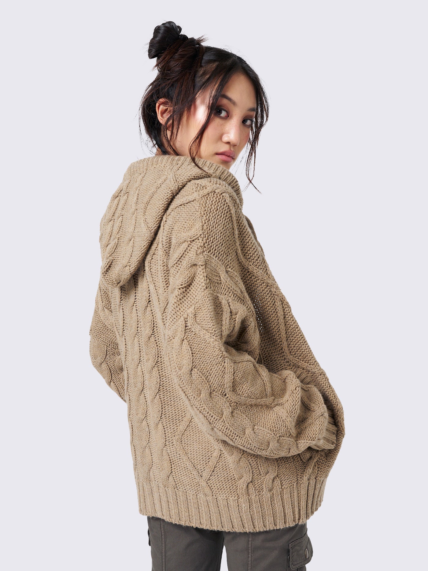 Oversized beige cable knit hooded cardigan with zip fastening and side pockets.