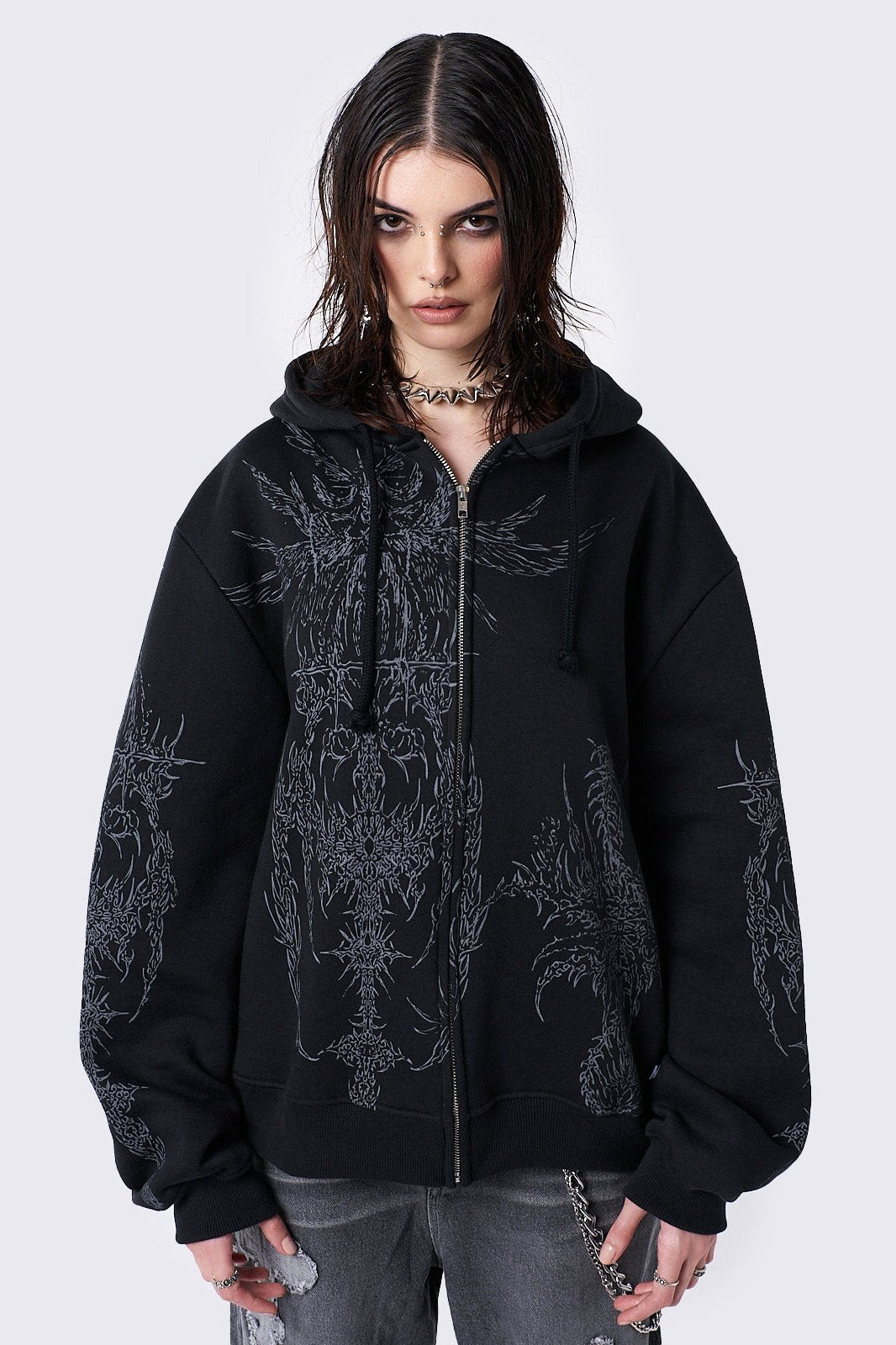 Oversized black zip-up hoodie with grunge graphic prints, drawstring hood, and ribbed trims. Y2K and acubi-inspired streetwear.