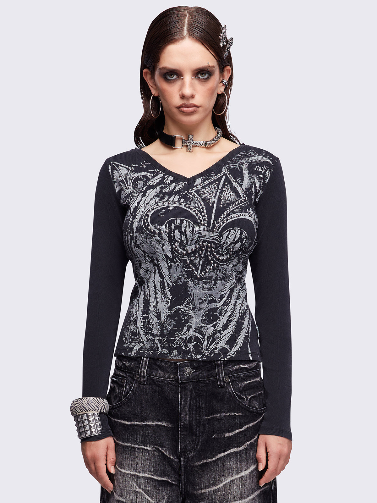 Black washed v-neck ribbed top featuring a fleur-de-lis graphic front print and silver stud details.