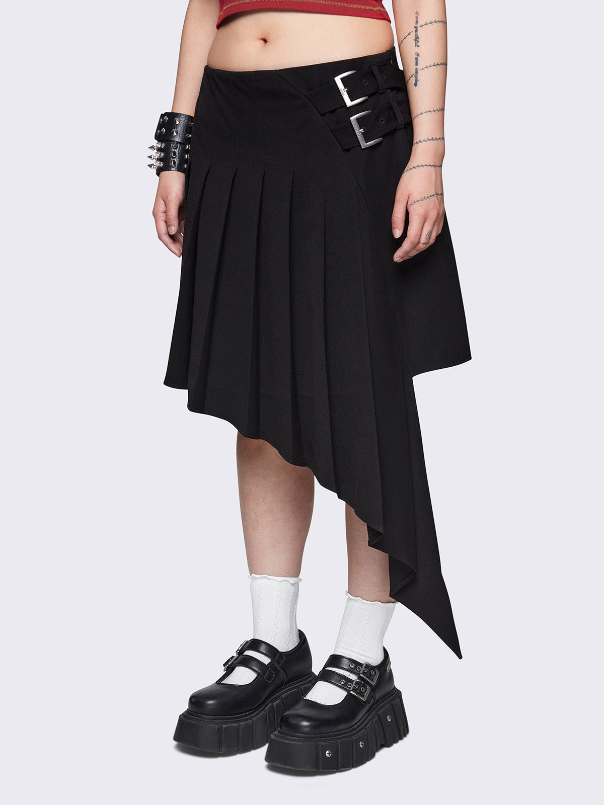 Pleated asymmetric midi skirt in black with double buckle and wrap effect.