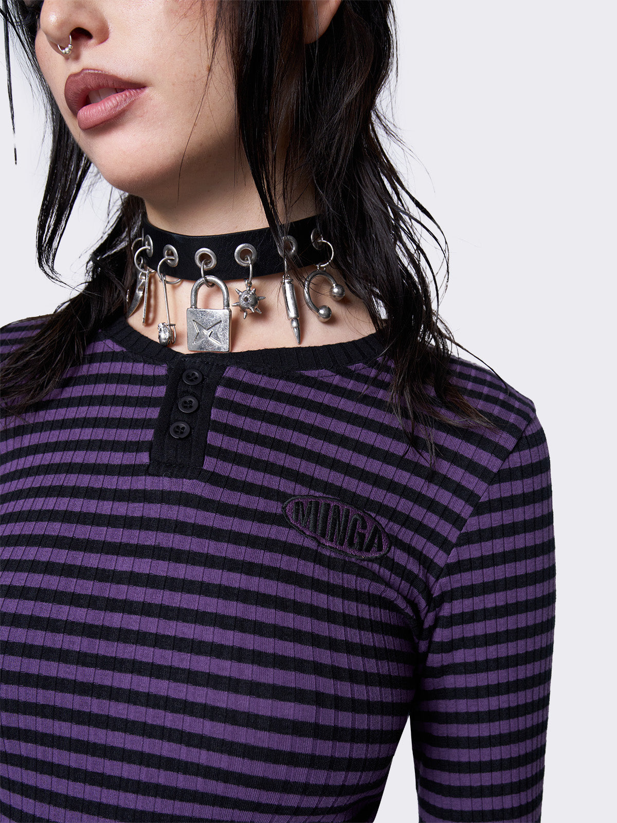 Slim-fit ribbed top with purple and black stripes, half button placket, Minga embroidered logo, and rounded neckline. Y2K and grunge-inspired style