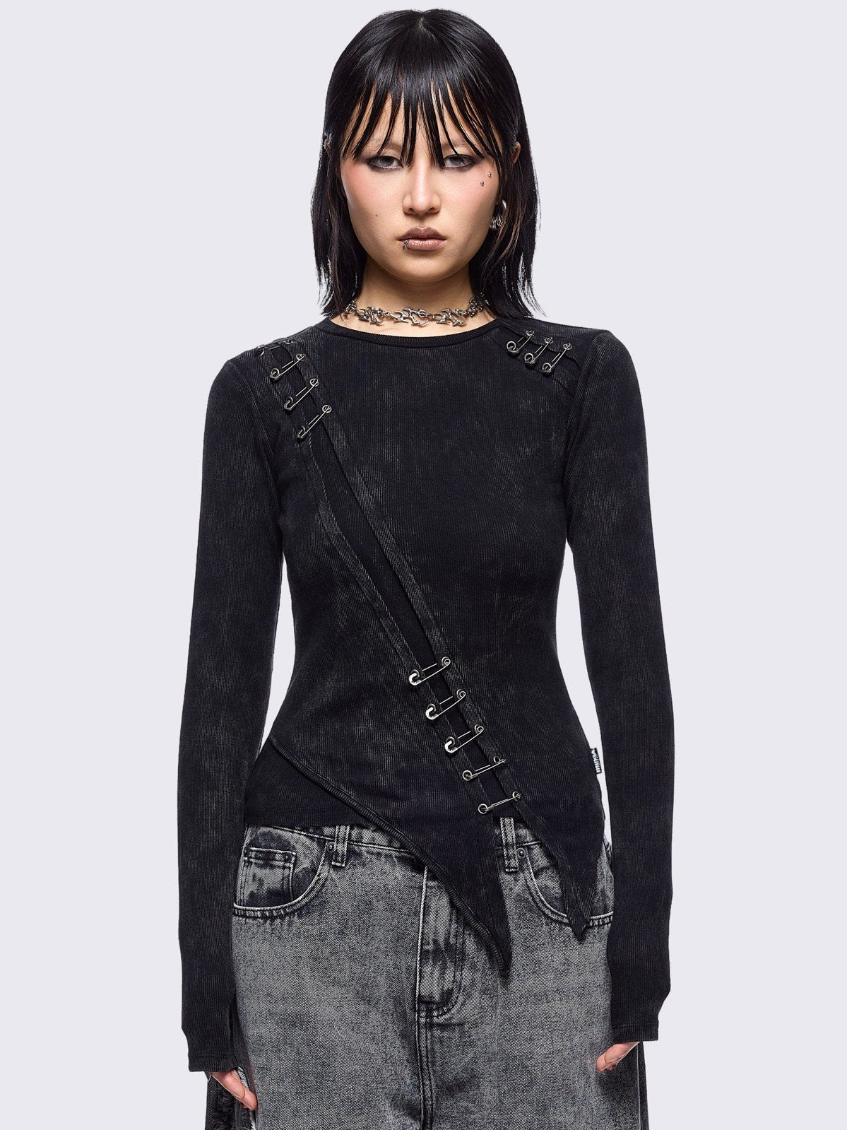 Black washed asymmetric top with cut-out and safety pin details.