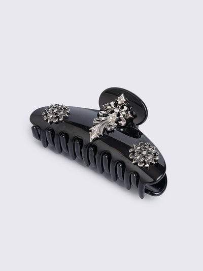 Black hair claw clip with silver floral baroque-style details.