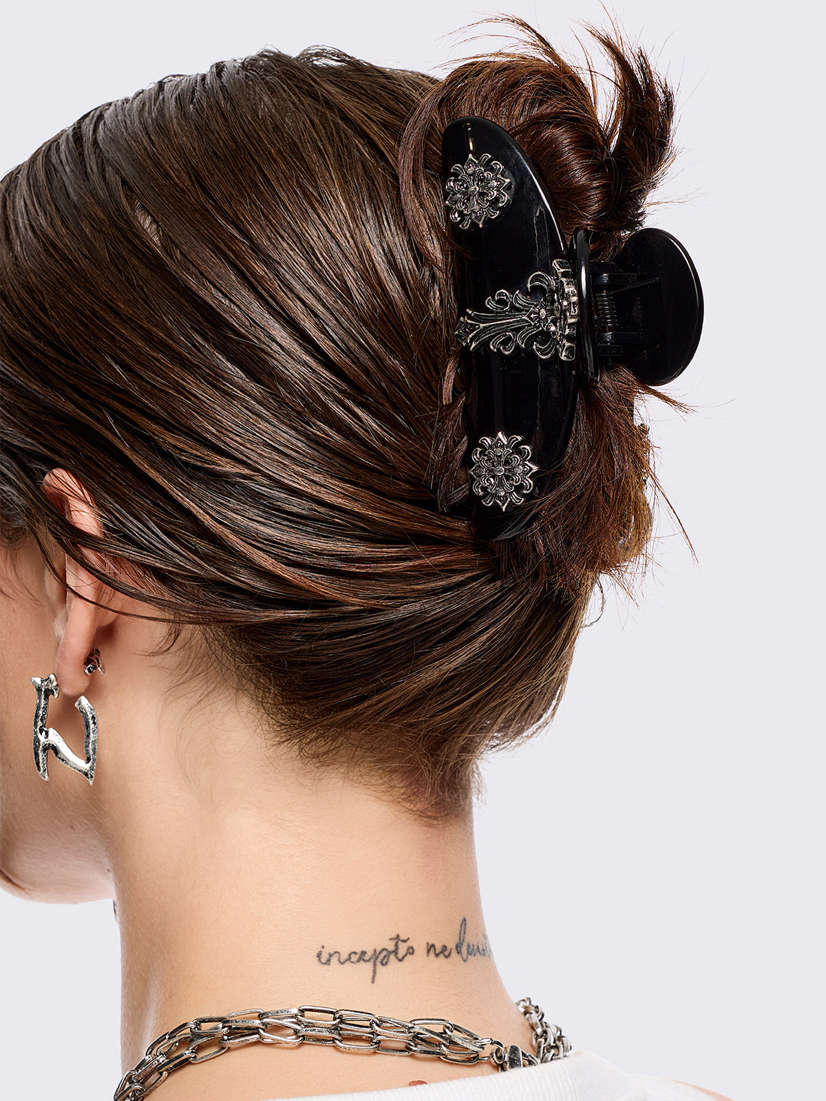 Black hair claw clip with silver floral baroque-style details.