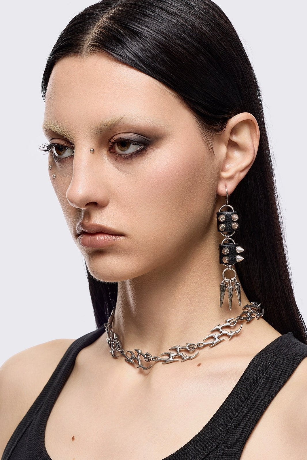 Silver dangle earrings with spiked pendants and black faux leather details