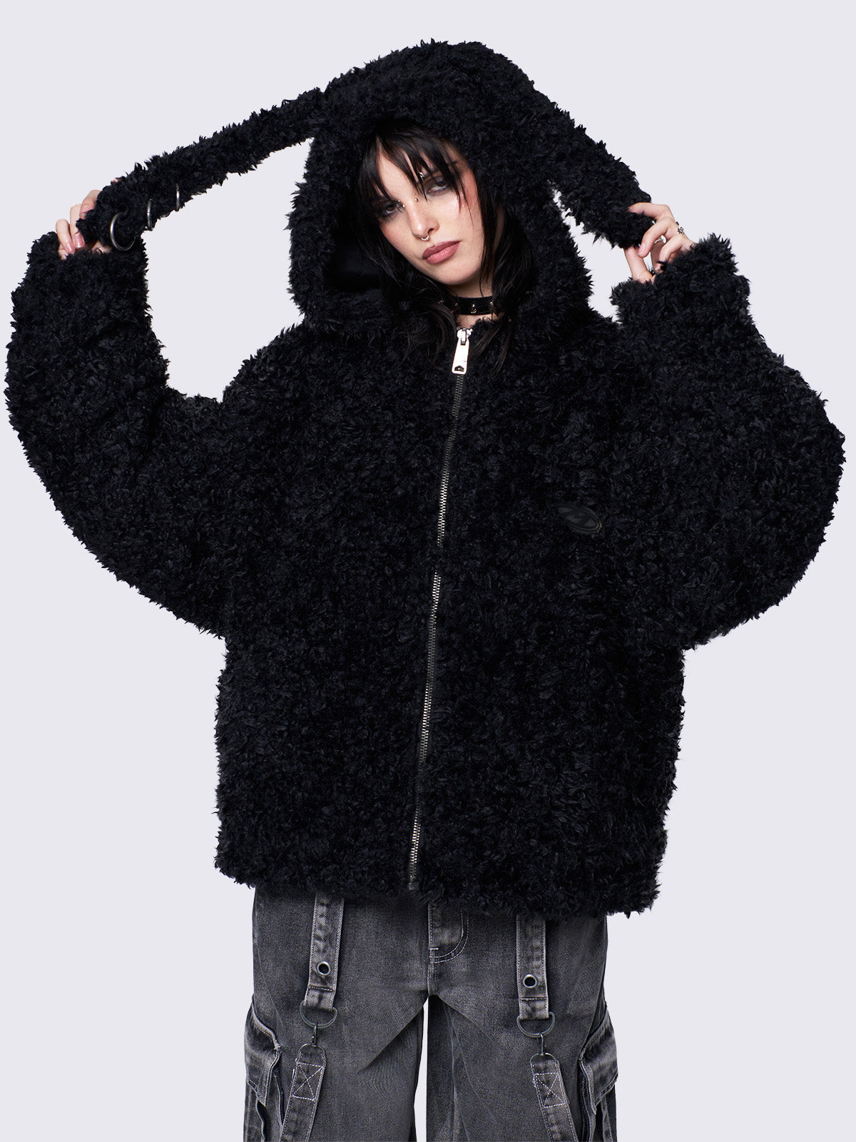 Black fuzzy zip-up jacket with bunny ear hood, oversized fit, and soft faux fur texture. 