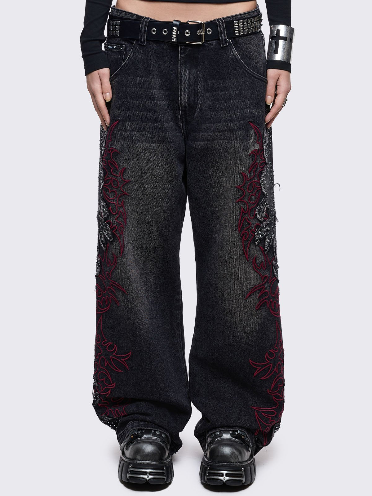 Black washed baggy jeans with grey overdye, frayed patches with silver studs and red sigilism embroideries. 