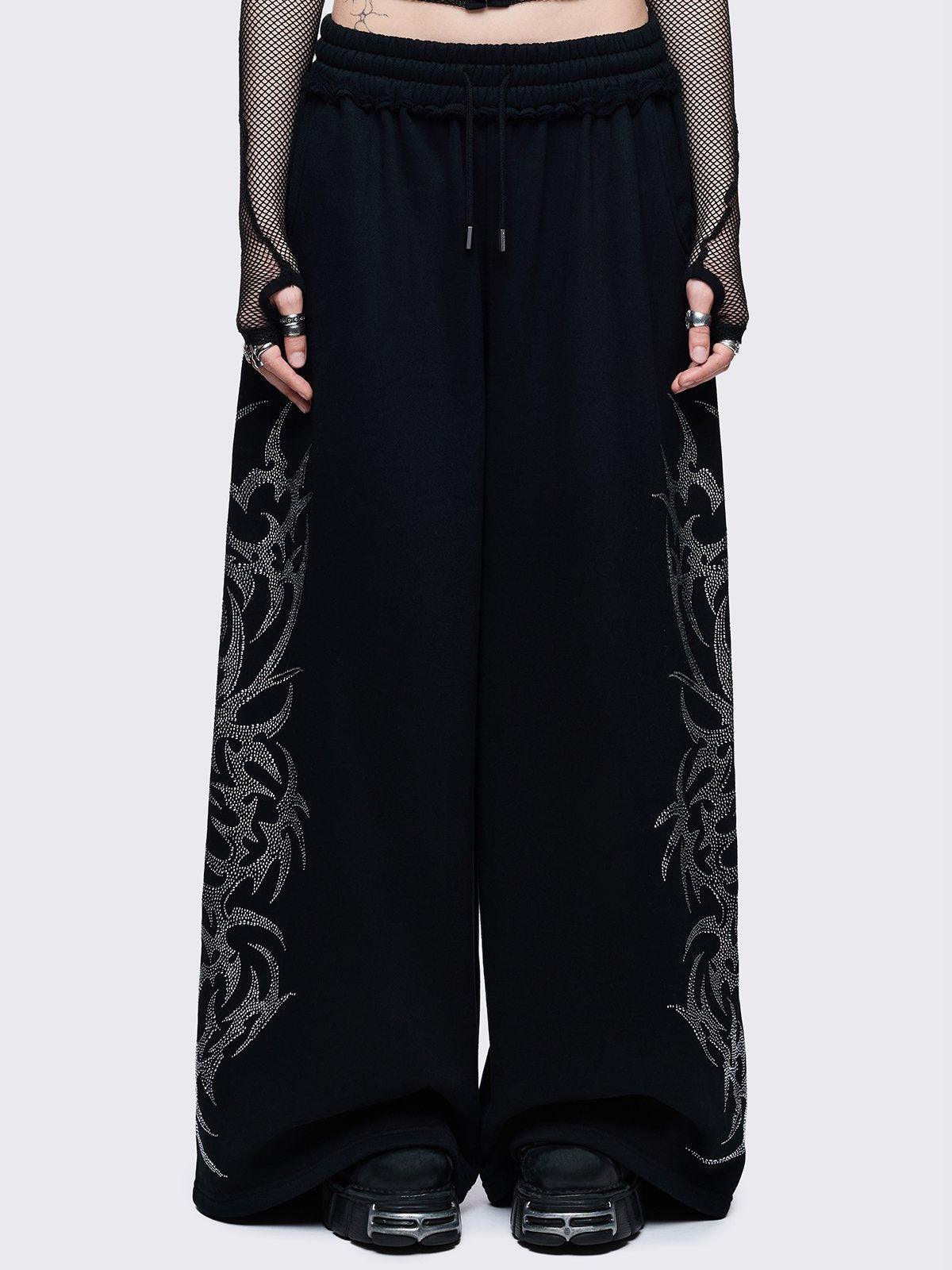 Loose-fit wide-leg sweatpants featuring a large, detailed tribal sigil pattern made of silver rhinestones running down the side seam.