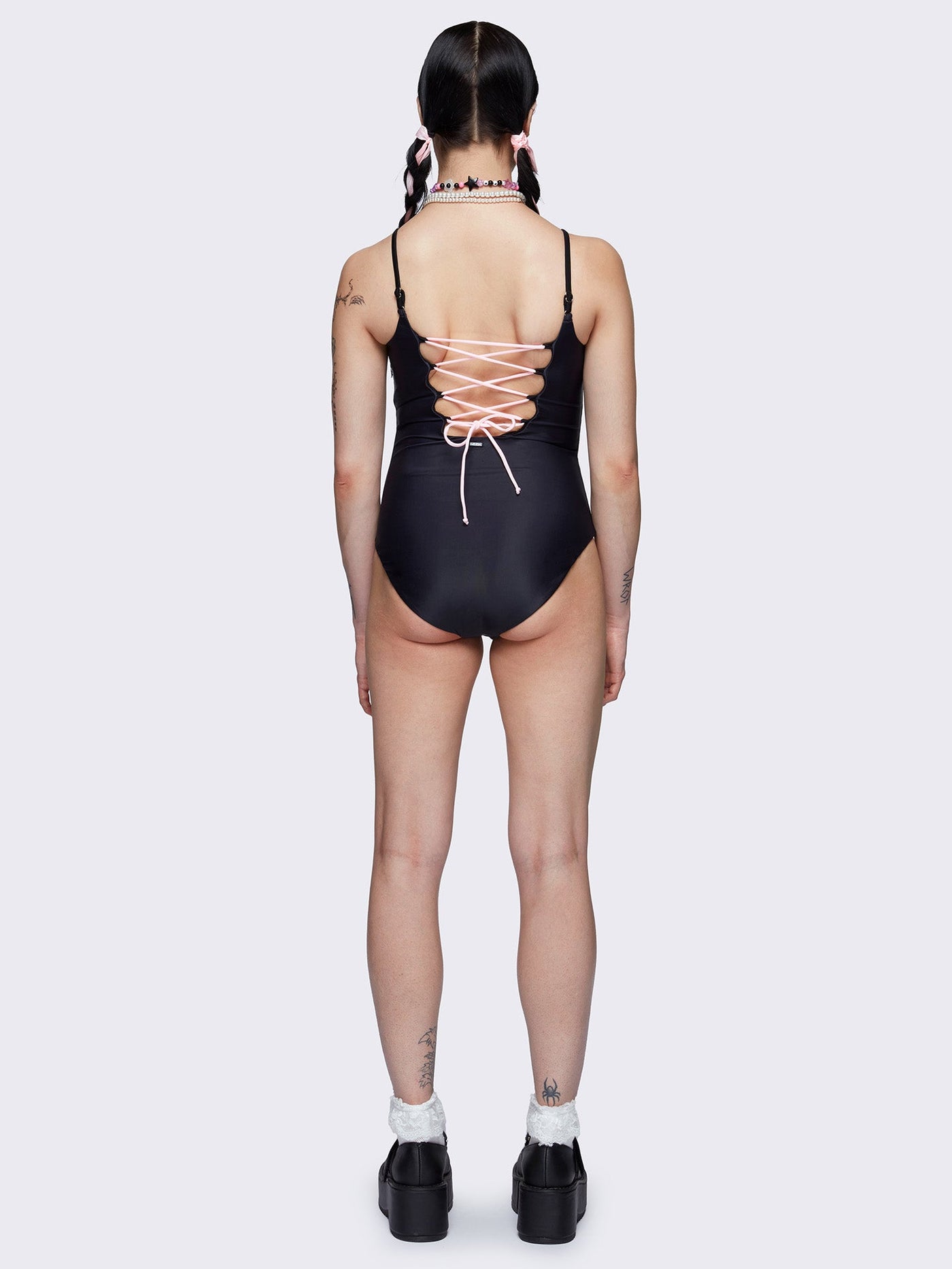 One-piece swimsuit in black with bunny graphic front print and pink laced up at back