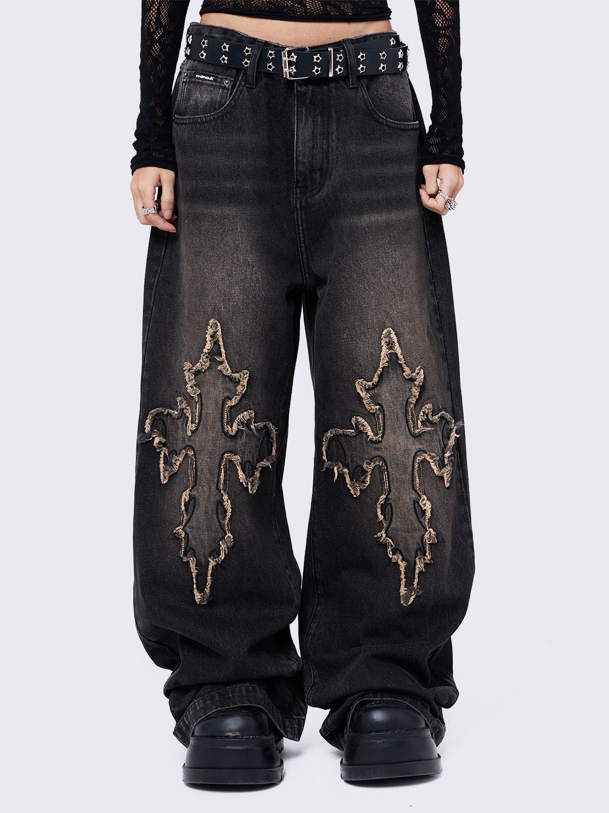 Black washed baggy jeans with brown overdye featuring a cross raw edge patches.