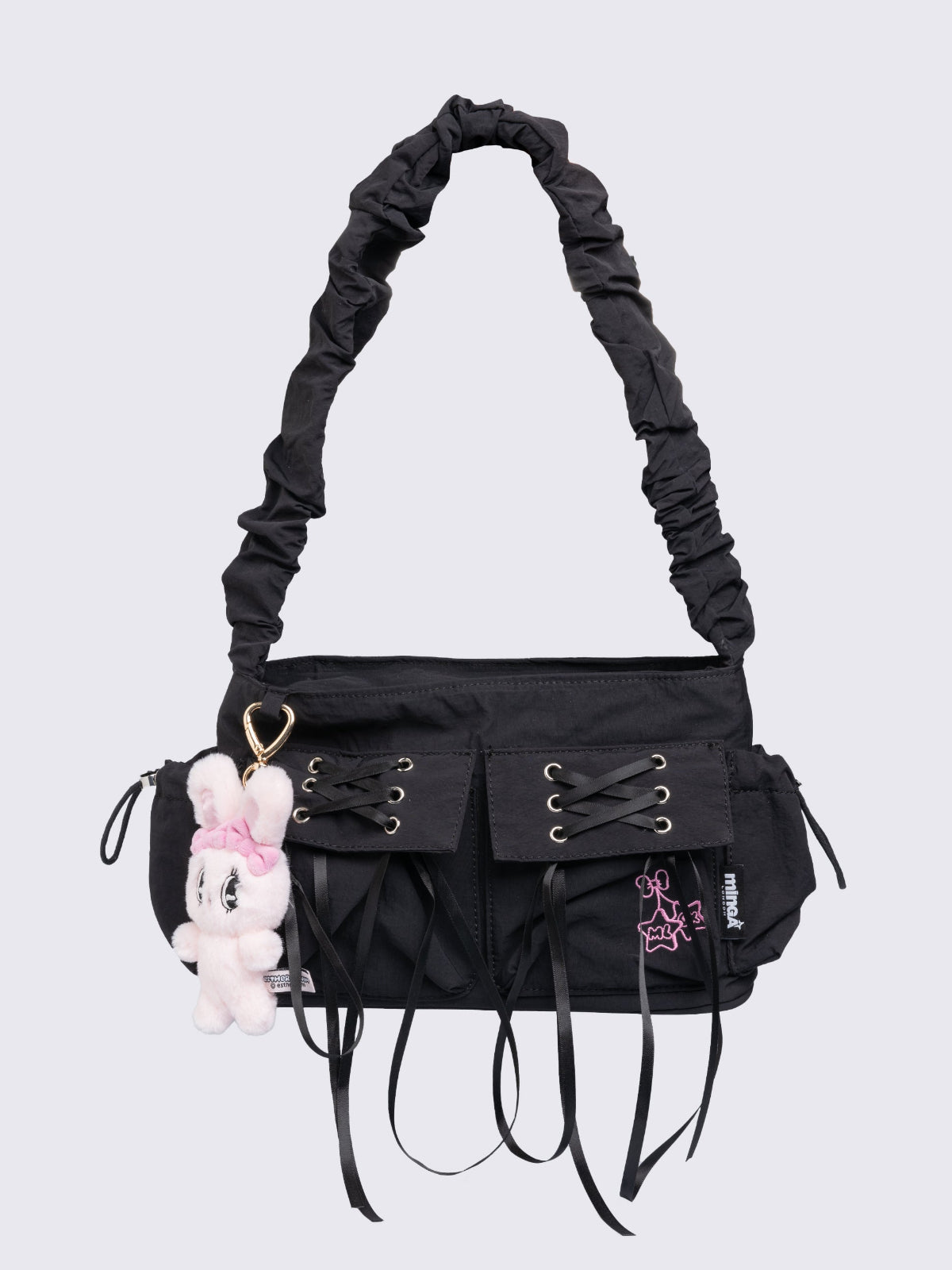 Black shoulder bag with ruched strap, lace-up ribbon front pockets, detachable plush pink bunny charm, and multiple pockets.