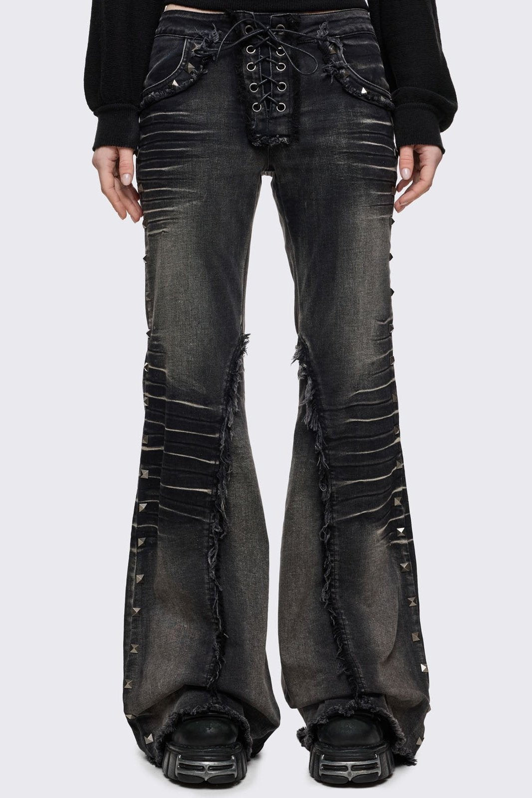 Black washed flared jeans with heavy whiskers, hardware details and a lace-up front closure. 