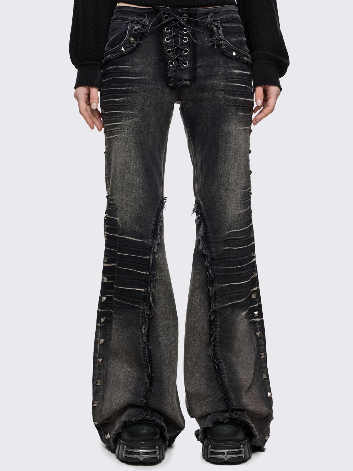 Black washed flared jeans with heavy whiskers, hardware details and a lace-up front closure. 