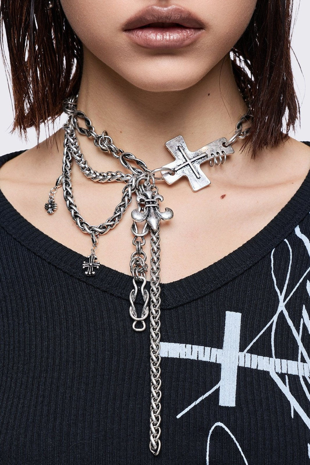 Layered necklace with chunky cross, fleur-de-lis and chain pendants.