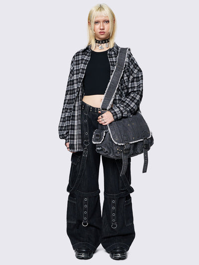 Black wash denim shoulder bag with frayed edges, flap closure, buckle straps, and studded details. Perfect for grunge and Y2K-inspired streetwear.