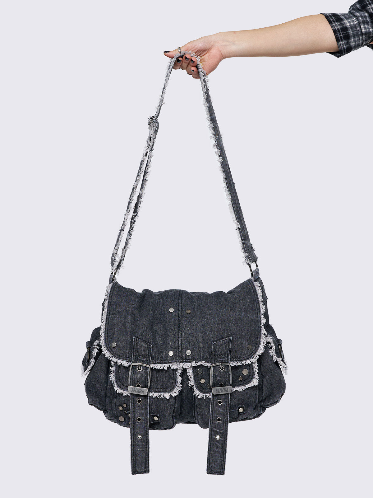 Black wash denim shoulder bag with frayed edges, flap closure, buckle straps, and studded details. Perfect for grunge and Y2K-inspired streetwear.