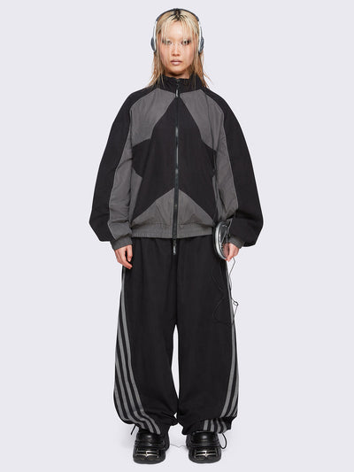 Black parachute pants with grey side stripes. 