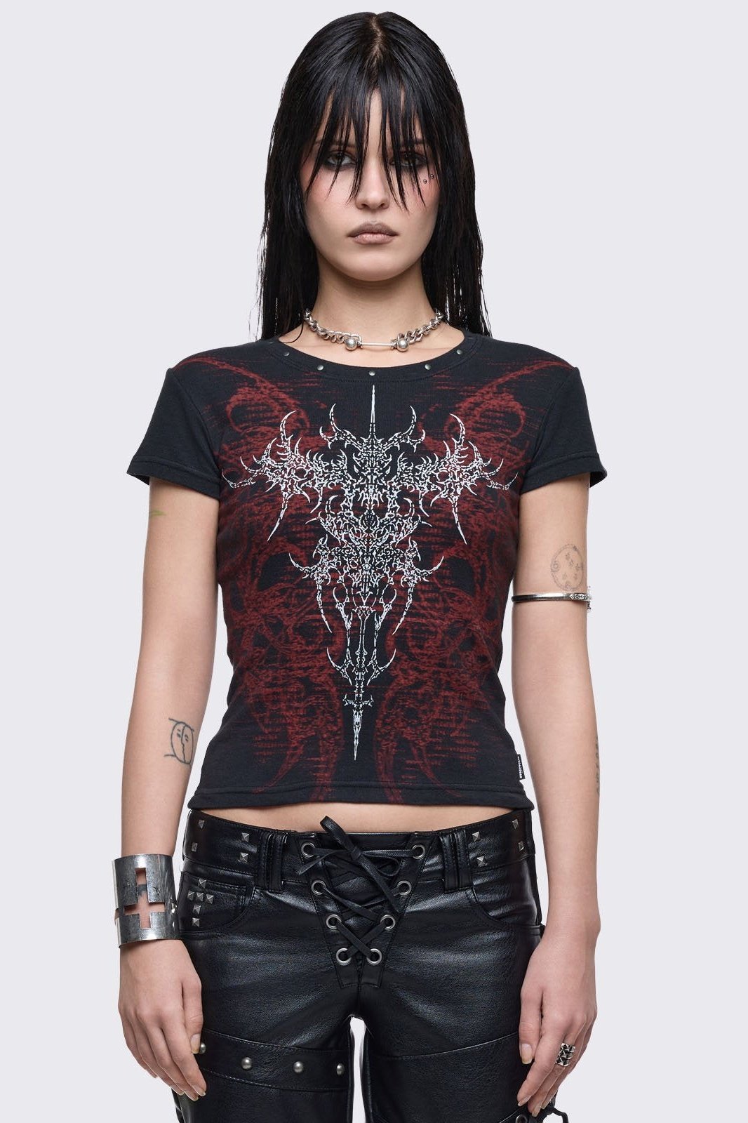 Black baby tee with red grunge graphic print and silver stud details.