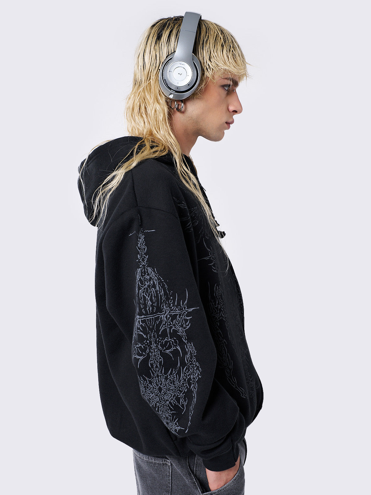 Oversized black zip-up hoodie with grunge graphic prints, drawstring hood, and ribbed trims. Y2K and acubi-inspired streetwear.