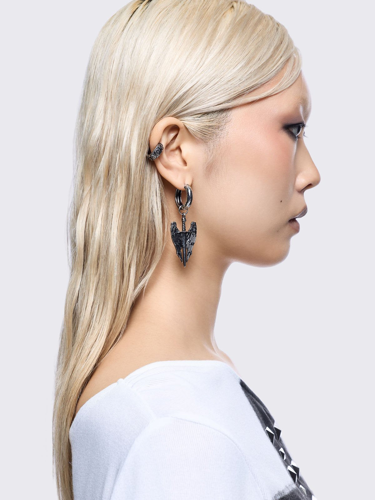 A 5-piece set of mismatched silver-toned earrings and an ear cuff featuring gothic and religious motifs, including crosses, a Virgin Mary medallion, and a winged sword dangle.