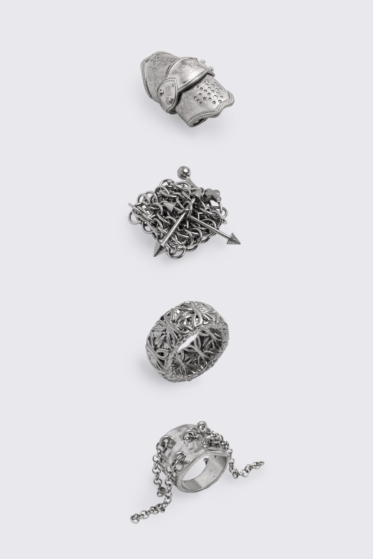 Chunky ring set in antique silver with armor, chain, and piercing details, goth-inspired statement jewelry.