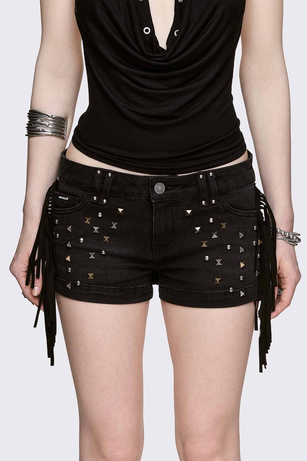 Black denim micro shorts with mixed studs and side fringe, low-rise fit in a grunge Y2K style.