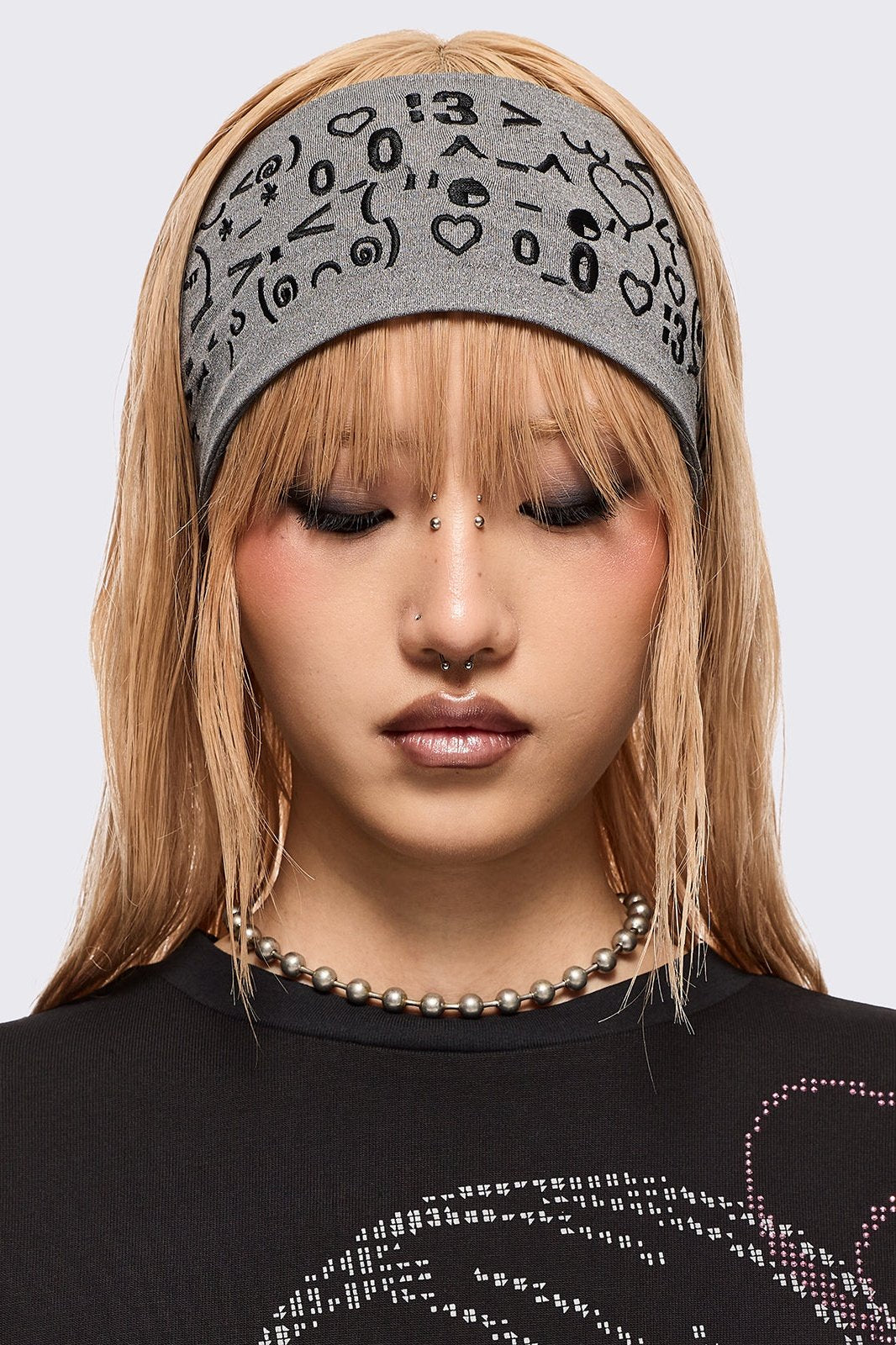 Grey wide headband with black kaomoji ASCII-style graphic embroidery.