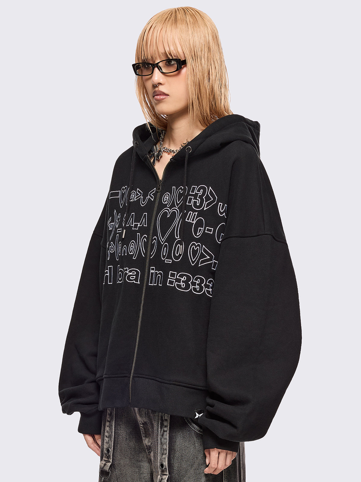 Black zip up hoodie jacket featuring a kaomoji ASCII-style embroidery in white.