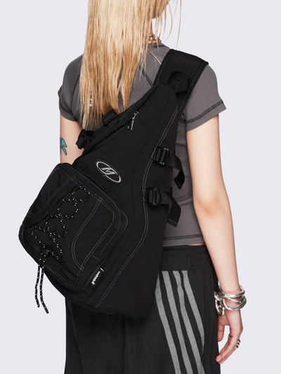 Black nylon sling bag featuring contrast stitching, multiple zip pockets and front bungee-cord detail.