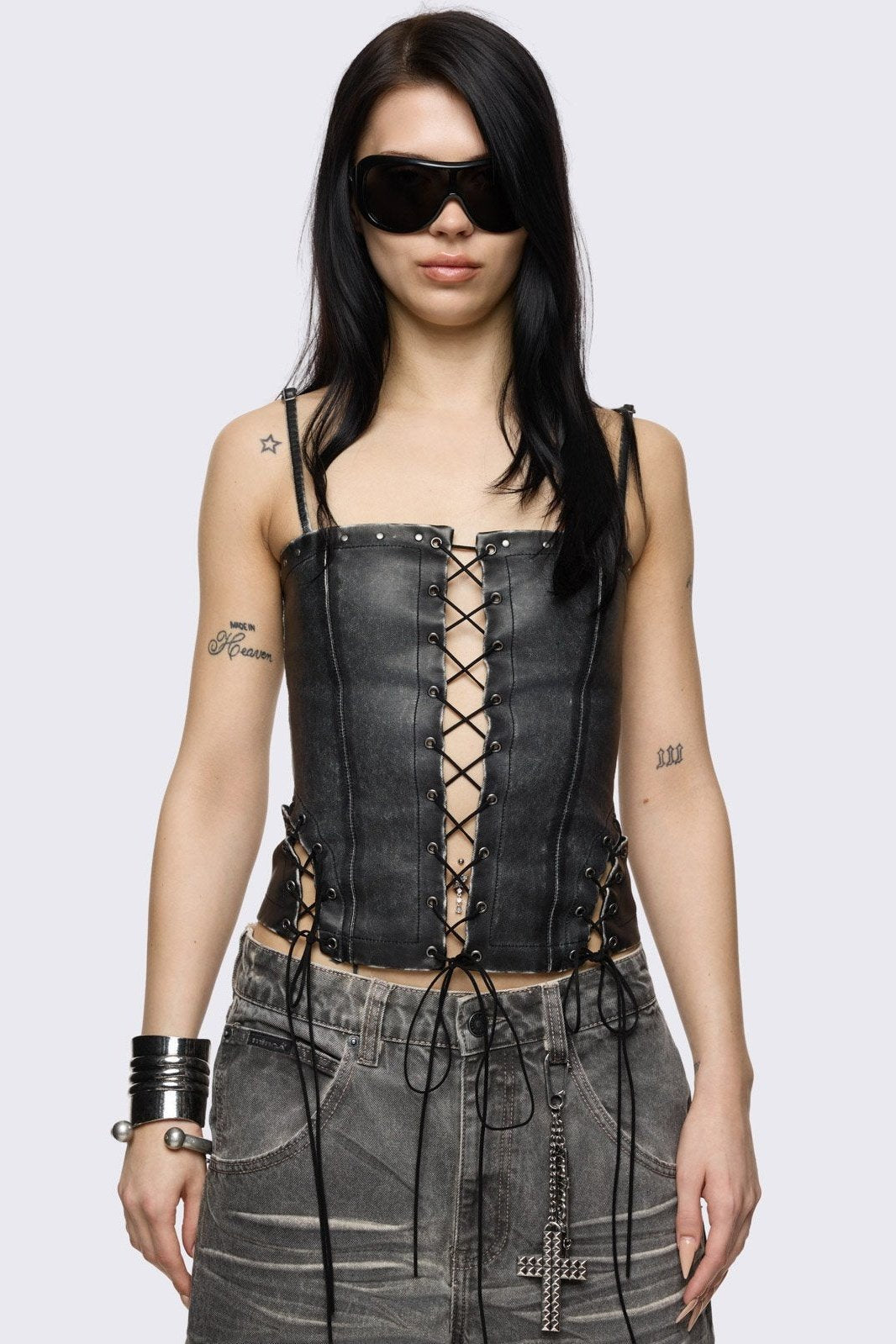 Washed faux-leather corset top featuring a central lace-up front, side cut-out lacing, and silver metal studs along the edges.
