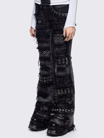 Black washed flare jeans featuring heavy distressed and shedded, eyelet, piercing and stud details. 
