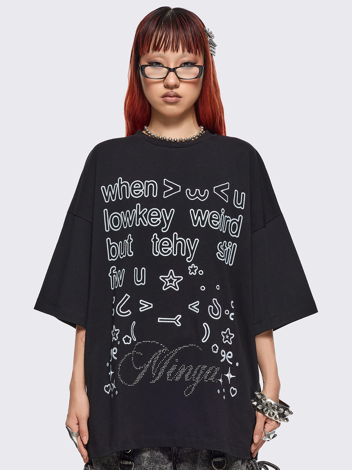 Black oversized t-shirt with "when u lowkey weird but tehy stil fw u" graphic print, kaomoji ASCII-style embroideries and stud details.