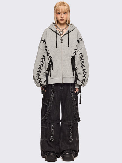 Grey marl zip-up hoodie with black lace corset details along the sleeves and front. Features a drawstring hood, zip fastening, long sleeves, and an oversized fit.