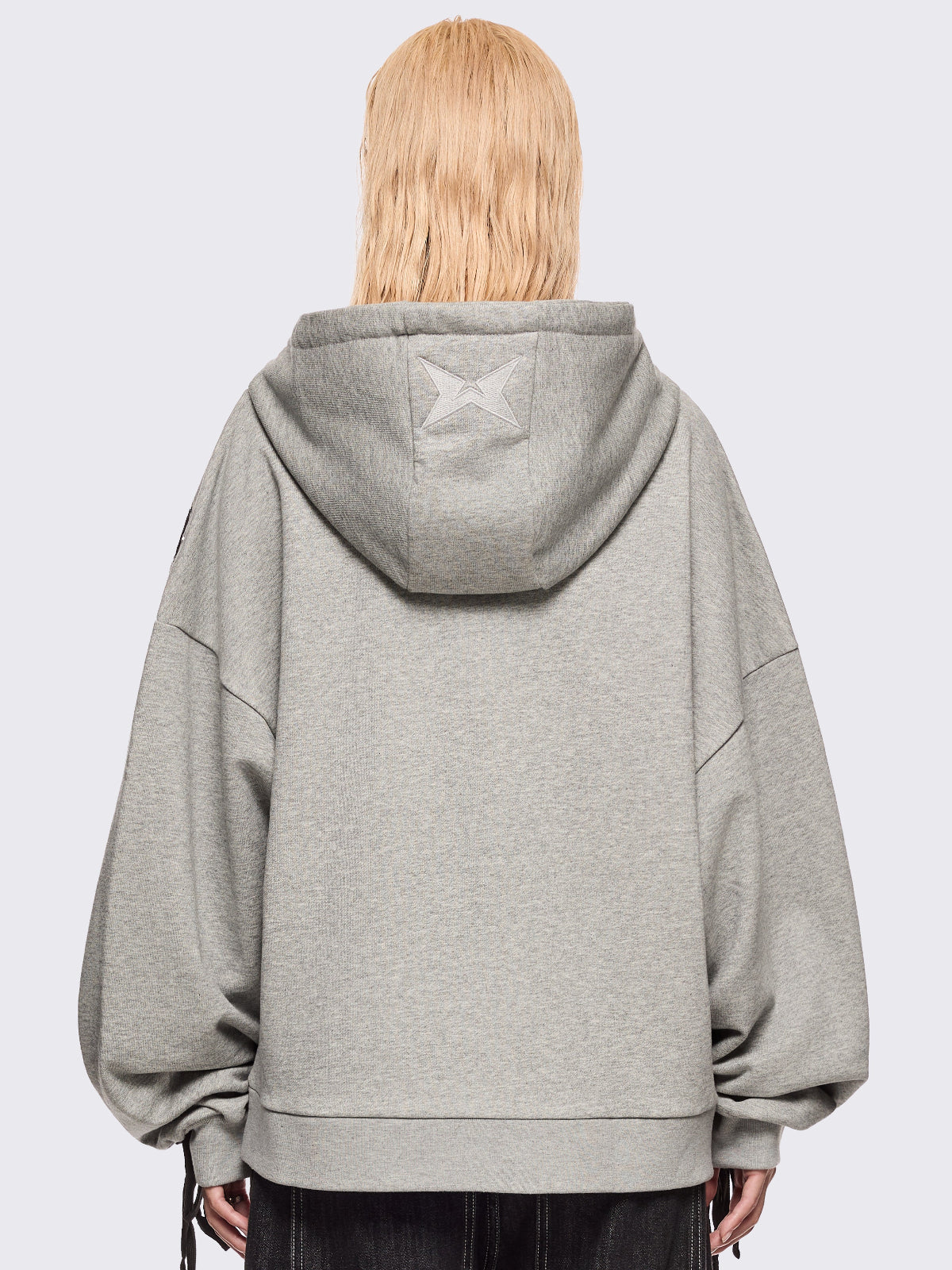 Grey marl zip-up hoodie with black lace corset details along the sleeves and front. Features a drawstring hood, zip fastening, long sleeves, and an oversized fit.