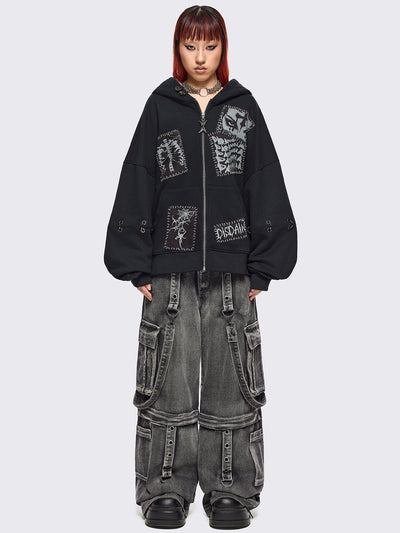 Black zip up hoodie jacket with white grunge print patches and eyelets with O-ring and piercing details.