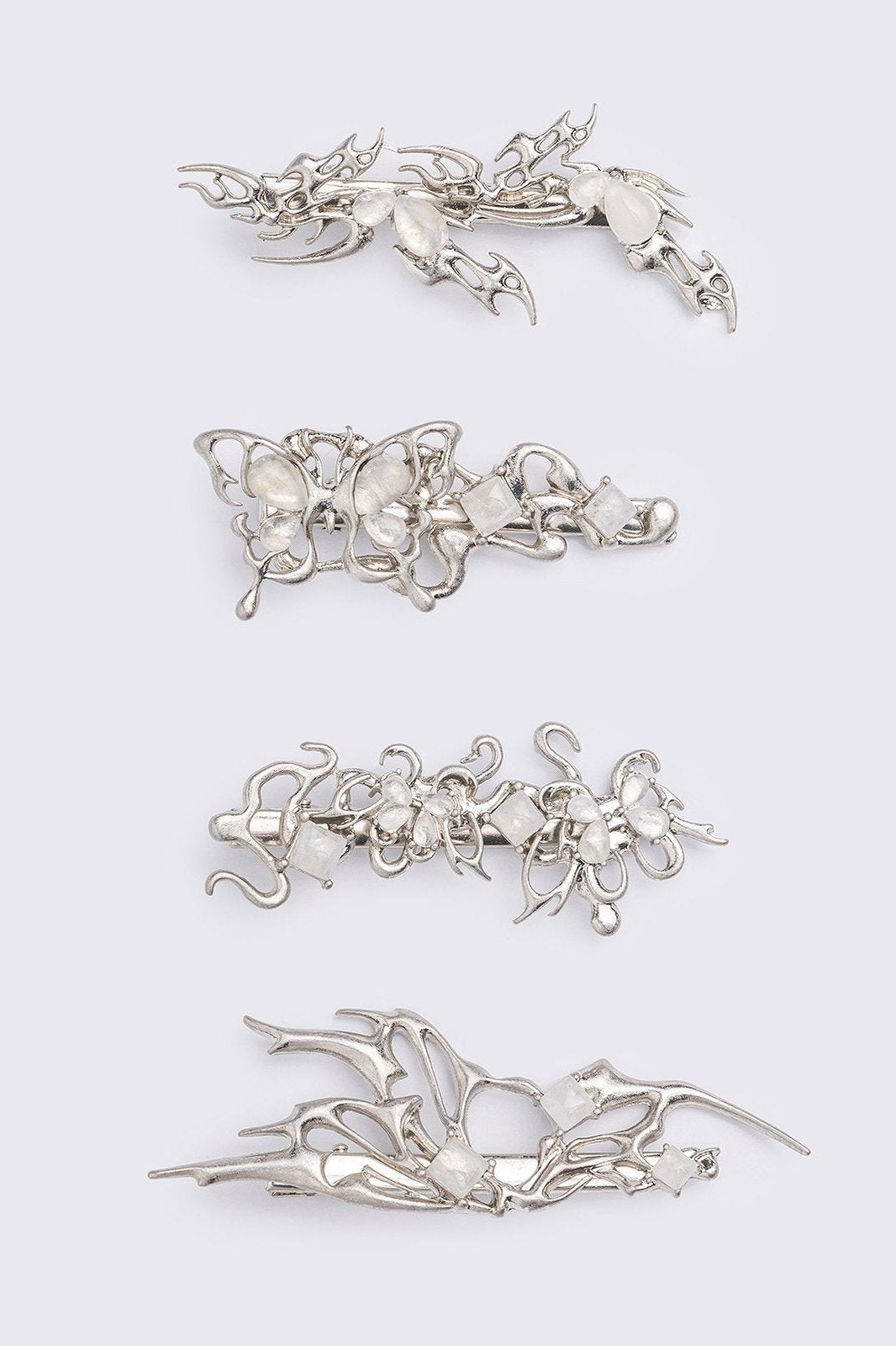 Set of 4 hair clips with butterflies and sigilism design and white stone details.