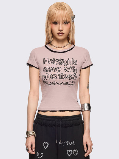 Baby pink graphic baby tee with "Hot girls sleep with plushies" graphic front print and black lace trims at seams.