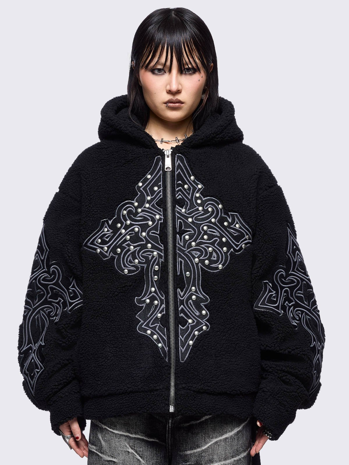 Black fleece hoodie jacket featuring a cross patch on front and sleeves and silver stud details.
