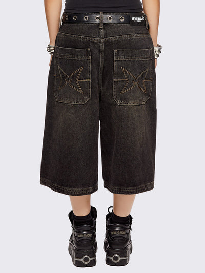 Black washed longline denim shorts with star-shaped stud and seam detail on front.