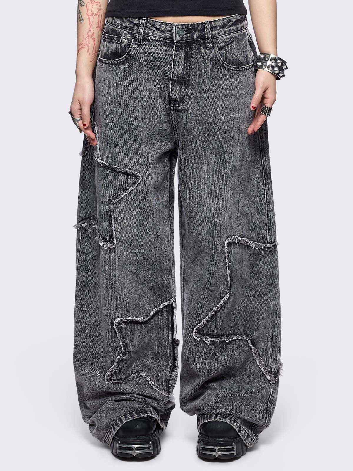 Grey washed baggy jeans with frayed star patches.