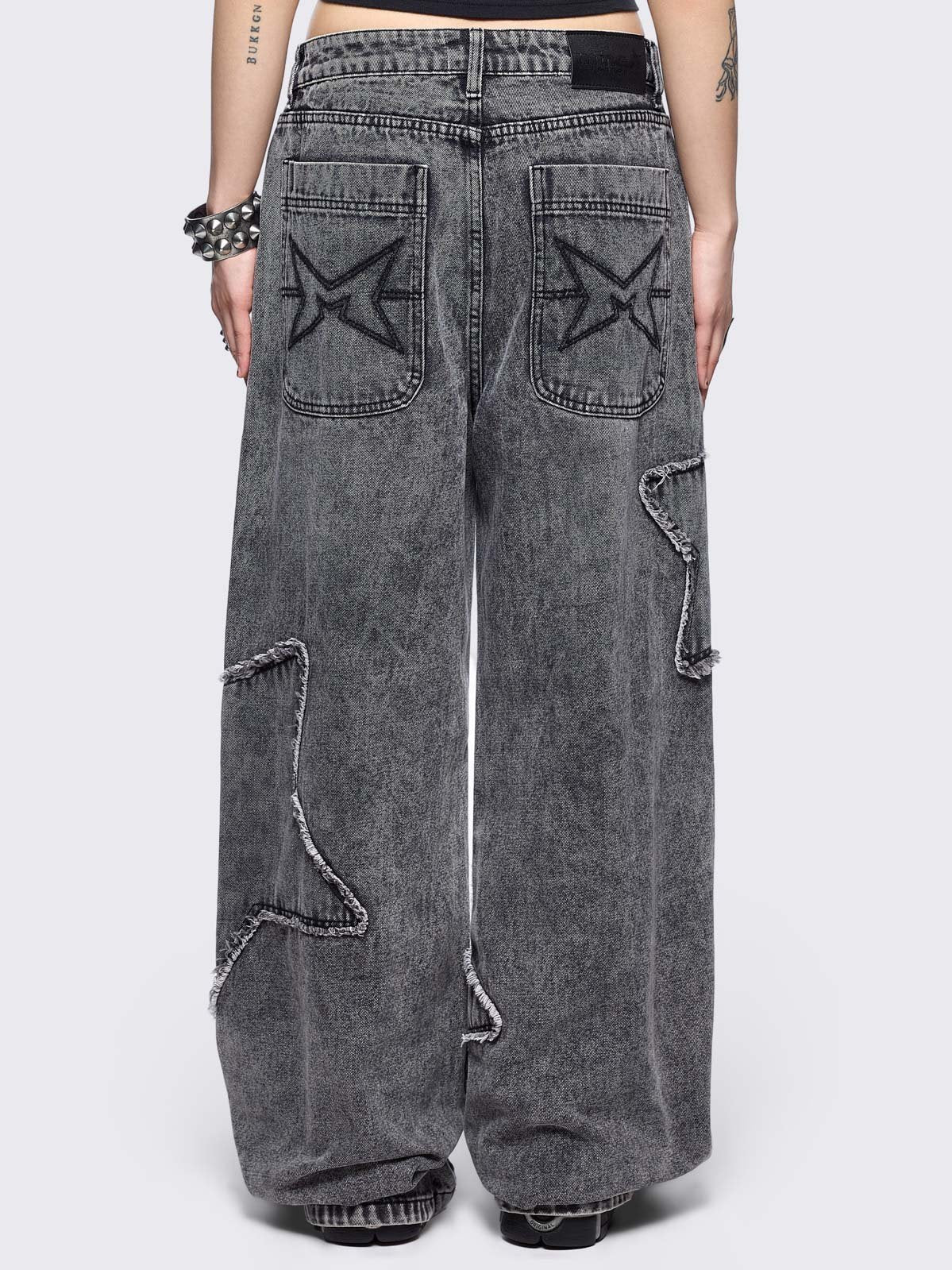 Grey washed baggy jeans with frayed star patches.